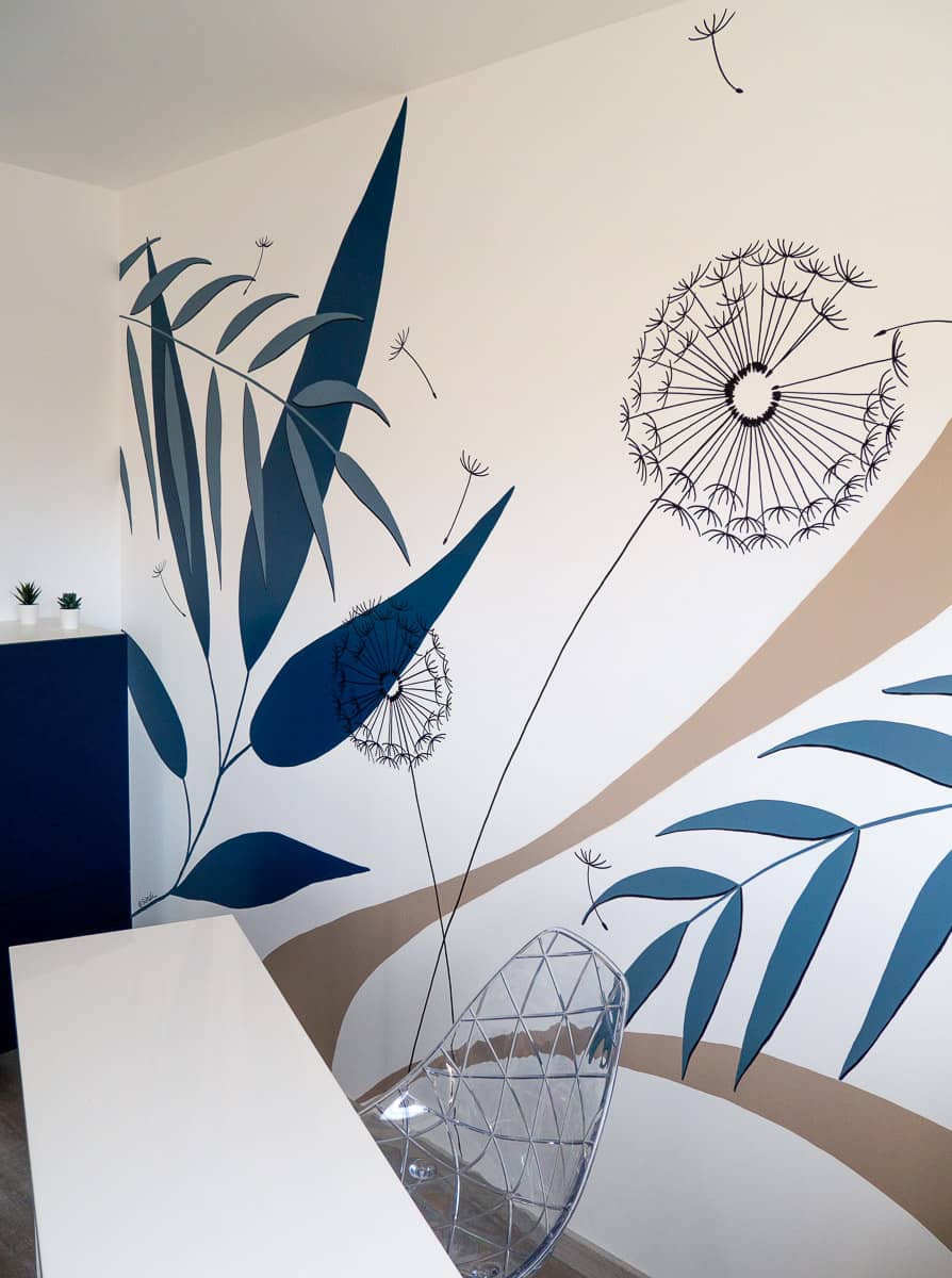 Zoom sur la fresque murale décorant un bureau avec des motifs végétaux, bleu marine et beige, pissenlit et feuilles tropicales