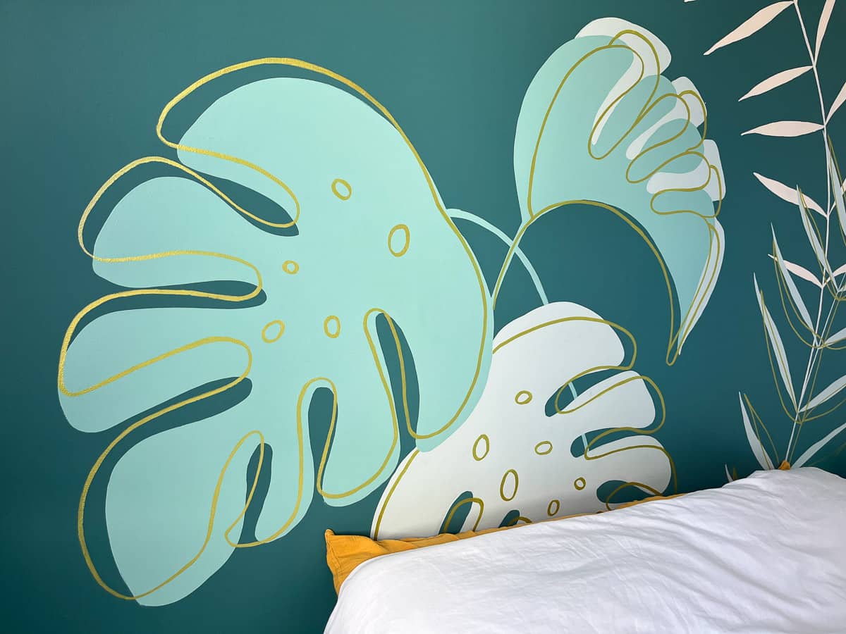 Fresque murale chambre adolescente peinte sur mesure. Gros plan sur les feuilles de monstera, sur fond vert canard, rehaussés de touches dorées.