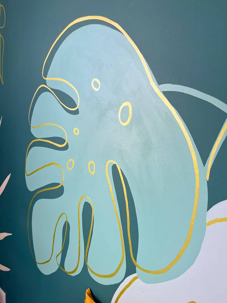 Gros plan, fresque murale chambre adolescente feuille monstera fond vert canard et lignes dorées