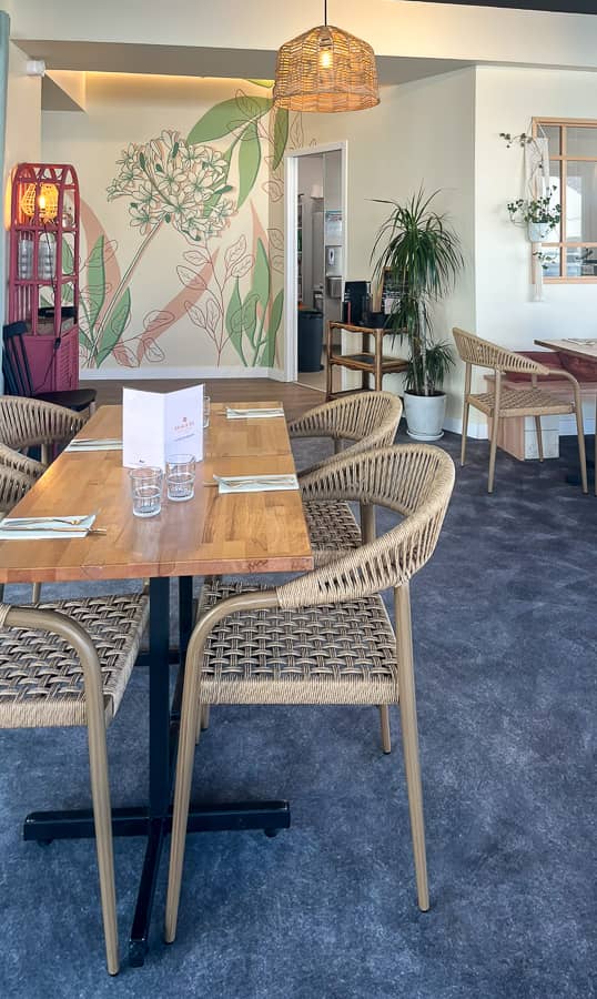 Fresque murale restaurant peinte sur mesure : agapanthe et feuillages en rose poudré et vert sauge sur fond blanc crème. Une décoration murale végétale qui crée une identité visuelle forte et une ambiance chaleureuse pour vos clients.
