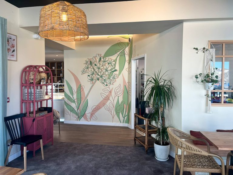 Fresque murale restaurant aux motifs botaniques rose et vert, agapanthe et feuillages graphiques sur mur blanc
