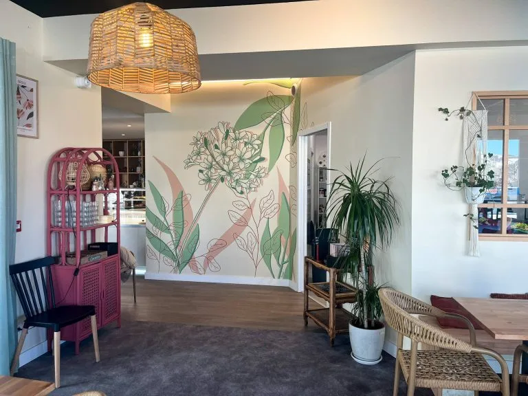 Fresque murale restaurant aux motifs botaniques rose et vert, agapanthe et feuillages graphiques sur mur blanc
